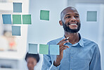 Black man, writing and planning schedule with smile on glass board for brainstorming tasks at office. Happy African American male smiling in project plan, post it or sticky note for company strategy
