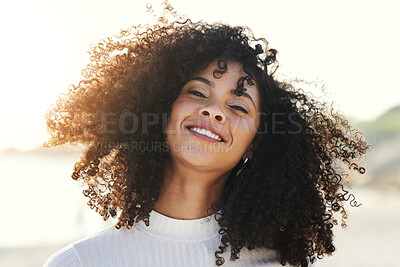 Buy stock photo Black woman, afro and wind in hair outdoor with a smile and portrait at beach for vacation or freedom. Face of happy young model person in nature for peace, travel and time to relax on sunset holiday