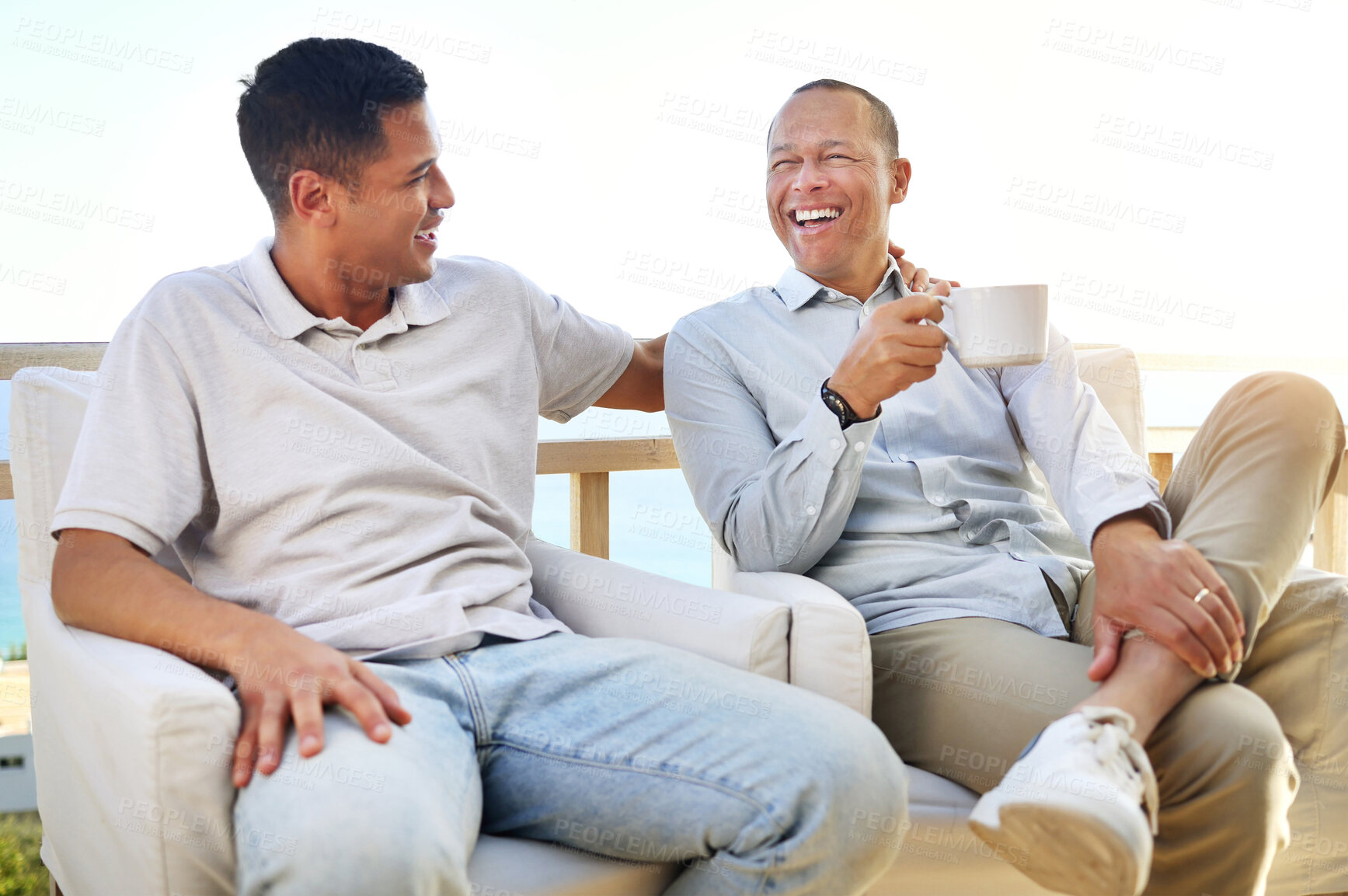 Buy stock photo Laughing, talking and father and son with coffee, bonding and speaking during visit. Family, happy and dad with an adult man for communication about a funny story, conversation and tea on the balcony