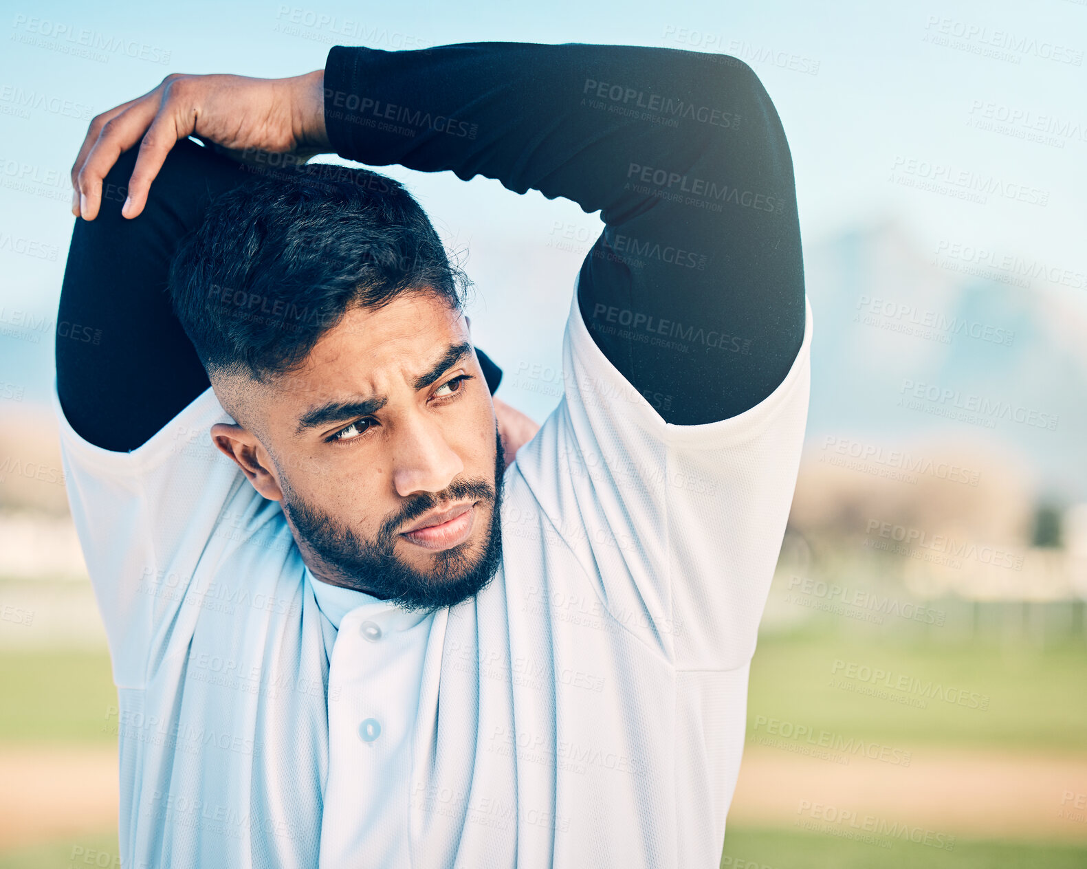 Buy stock photo Stretching, sports and man thinking at a baseball game for focus, motivation and training idea. Fitness, exercise and athlete with an arm warm up ready to start a competitive match on a field