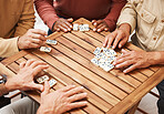 Hands, dominoes and friends in board games on wooden table for fun activity, social bonding or gathering. Hand of domino players with rectangle number blocks playing in group for entertainment