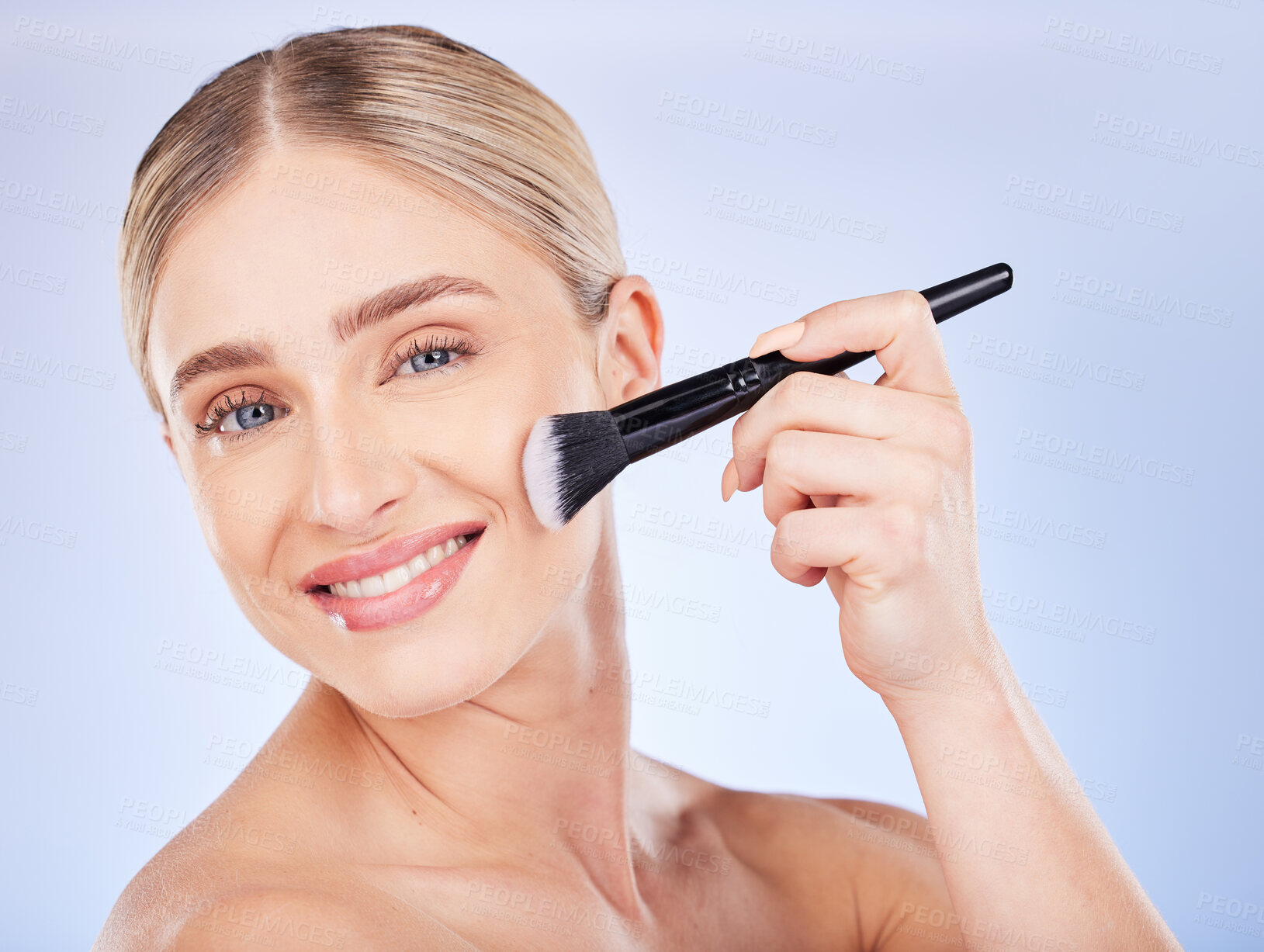 Buy stock photo Portrait, face and makeup of woman with brush in studio isolated on a blue background. Facial cosmetics, beauty skincare and happy female model with tool to apply foundation or powder for aesthetics.