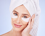 Skincare, face and woman with eye patches in studio isolated on a blue background. Dermatology portrait, beauty cosmetics and happy female model with towel and collagen facial mask for healthy skin.