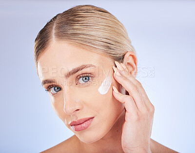 Buy stock photo Face portrait, skincare and woman with cream in studio isolated on a blue background. Facial dermatology, beauty cosmetics and young female model apply hydration lotion, creme or moisturizer product