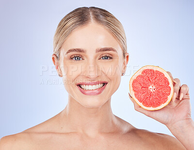 Face portrait, skincare and woman with grapefruit in studio isolated on a blue background. Food, fruit and happy female model with citrus for vitamin c, nutrition or diet, healthy skin or beauty.