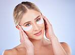 Face portrait, skincare and woman with eye mask in studio isolated on a blue background. Dermatology, makeup cosmetics and beauty of female model with facial patches for healthy skin or collagen.