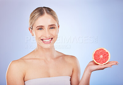 Skincare, face portrait and woman with grapefruit in studio isolated on a blue background. Food, fruit and happy female model with citrus for vitamin c, nutrition or diet, healthy skin or beauty.