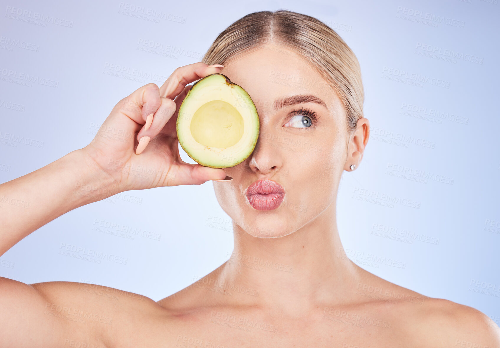 Buy stock photo Face, skincare and woman with avocado in studio isolated on a blue background. Cosmetics kiss, fruit and thinking female model with food for omega 3, nutrition or diet, healthy skin or beauty pout.