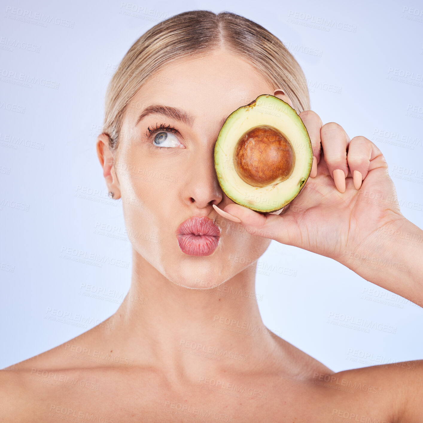 Buy stock photo Skincare, face and woman with avocado in studio isolated on a blue background. Cosmetics kiss, fruit and thinking female model with food for omega 3, nutrition or diet, healthy skin or beauty pout.