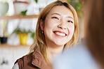 Face, happy or smile and an asian woman in a coffee shop, enjoying spending time with a friend. Cafe, brunch and lifestyle with an attractive young girl sitting in a restaurant for a chat or catch up