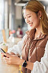 Phone, Asian or girl on social media in cafe with happy smile on holiday vacation or weekend alone. Dating app, female or young woman texting or typing a message in restaurant drinking a cocktail 