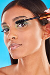 Indian woman, face and beauty with makeup and mascara, lashes and cosmetic product in portrait on blue background. Eyeshadow, eyelash extention with cosmetology, skincare and young female with glow