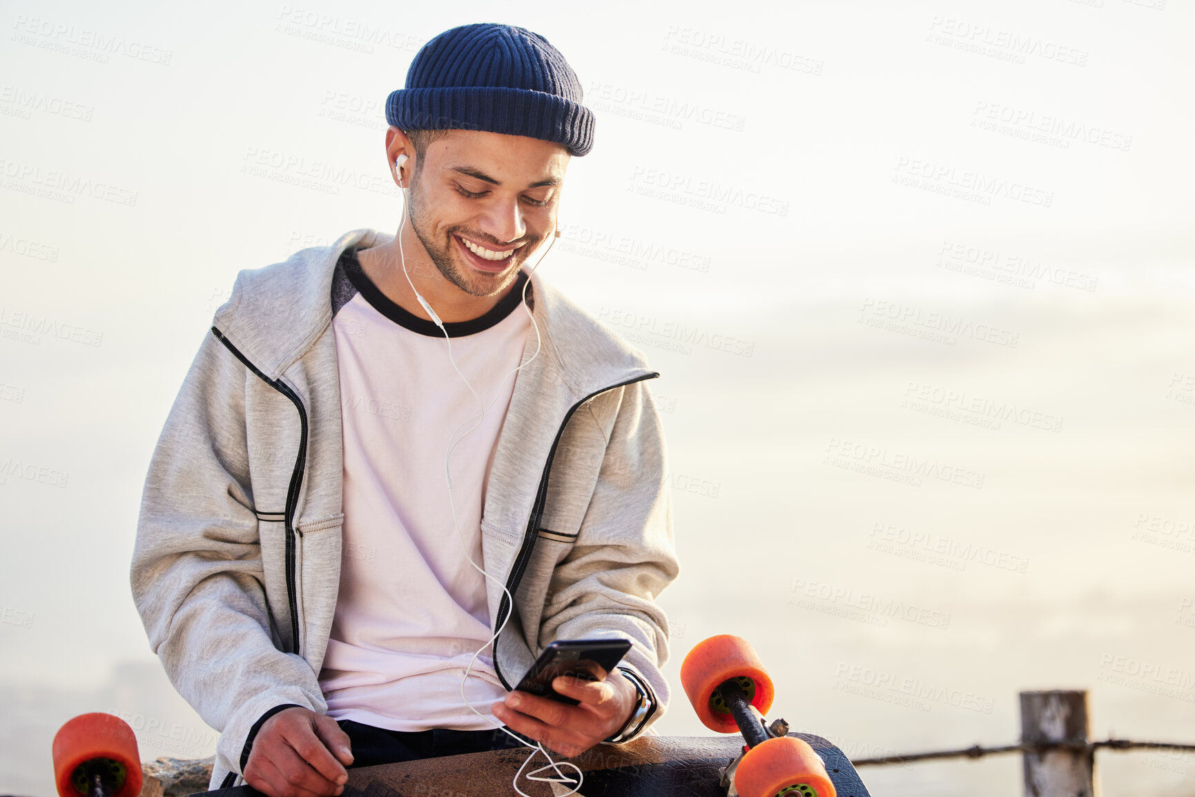 Buy stock photo Skateboarder, phone and man streaming music, audio or podcast online and relax after skating with mockup and texting. Skater, skateboard and person listening to mobile radio in sunset on social media