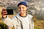 Fitness, selfie and male hiking on the mountain after walking for a wellness exercise in nature. Sports, health and young man hiker taking a picture while trekking outdoor for a cardio workout.