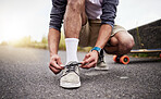 Hands, shoes and skate with a man tying his laces while on an asphalt skateboard for fun or recreation. Road, training or footwear with a male skater outdoor on a street while fastening his shoelaces