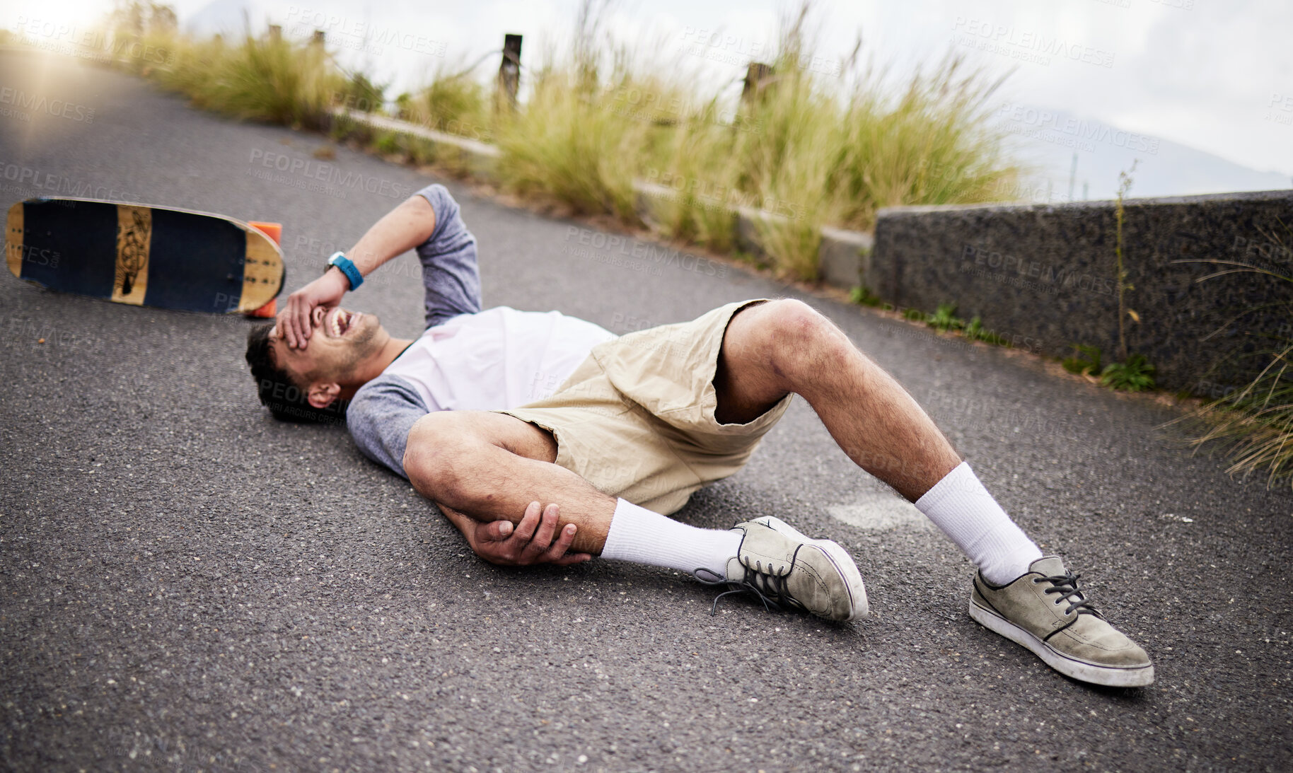 Buy stock photo Accident, fall and knee injury with a skater man on the ground, lying down in pain after falling down. Sports, training and anatomy with a young male suffering a skateboard emergency outdoor