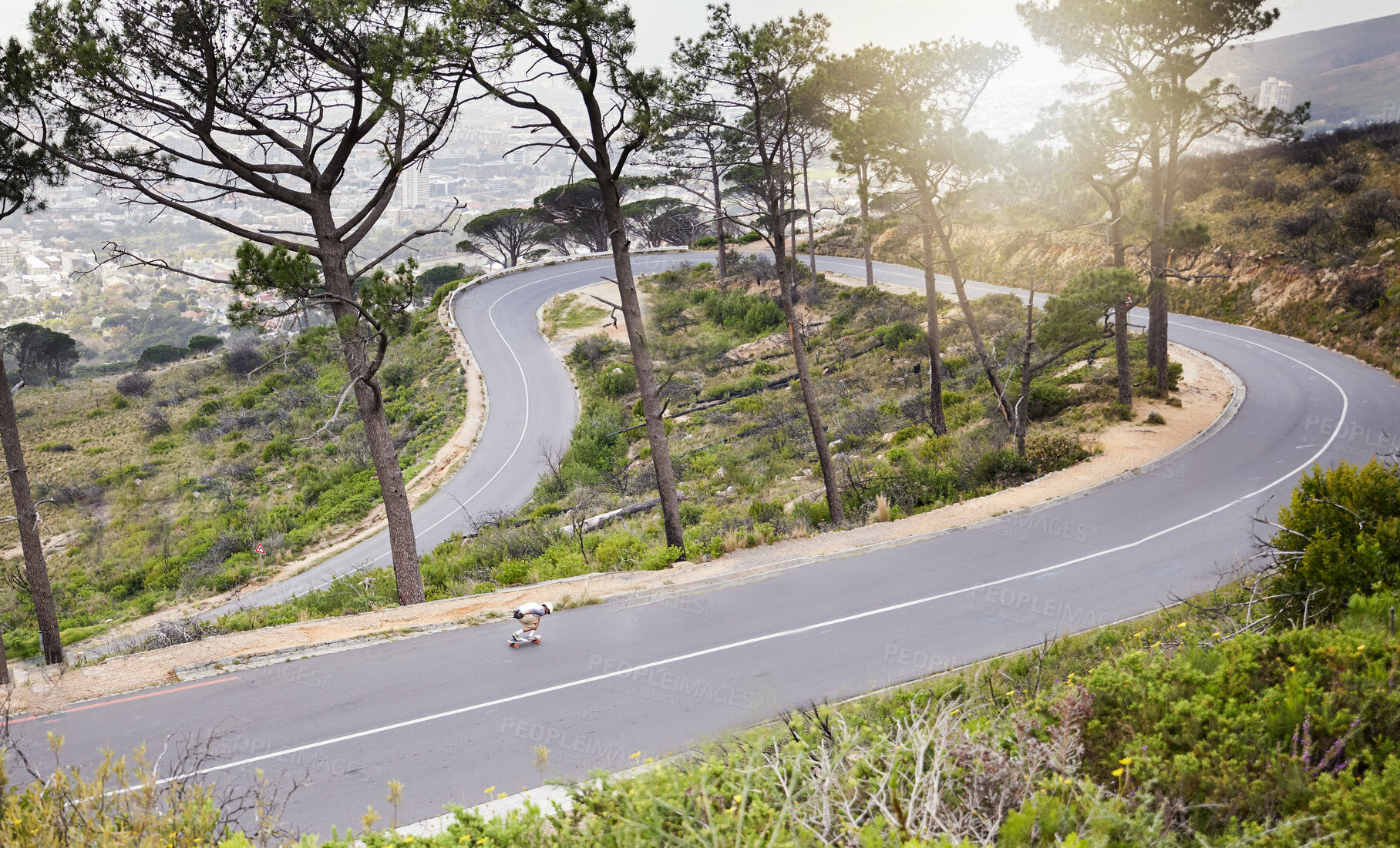 Buy stock photo Mountains, skateboard and fitness with man on winding road for training, speed and adventure. Freedom, youth and fast with guy skating in urban street of nature for exercise, wellness and challenge  