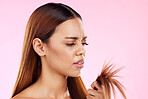 Woman, split end in hand and upset at hair in studio for salon, hairdresser or repair shampoo or treatment. Damage and dry texture or hairstyle of a beauty model frustrated on a pink background space