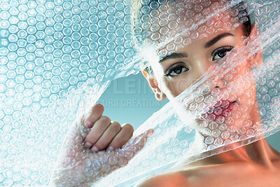 Buy stock photo Bubble wrap, beauty and portrait of woman with makeup, cosmetics and skincare products in studio. Creative art, salon aesthetic and girl with face glow, lipstick and luxury style with plastic tear