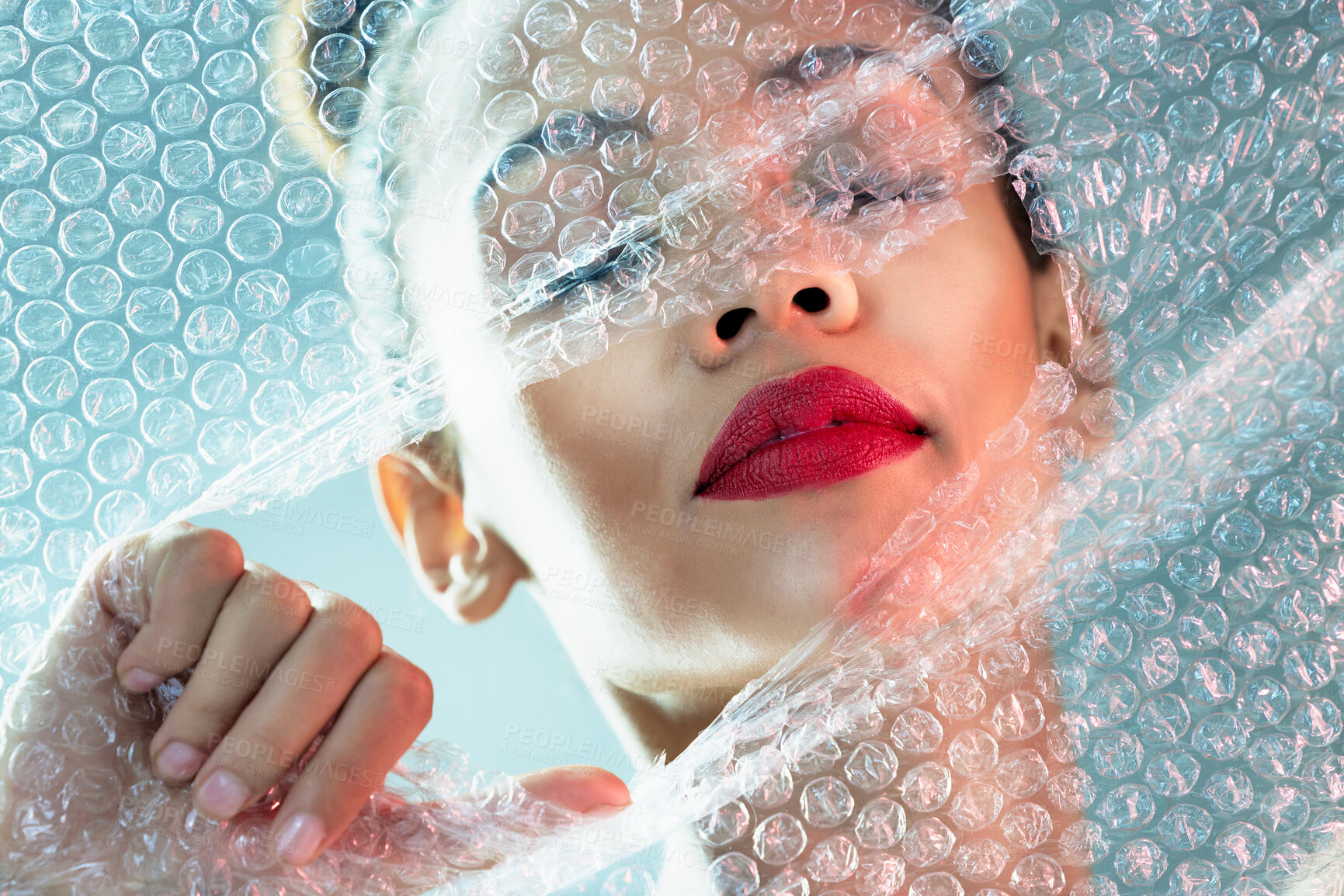 Buy stock photo Beauty, bubble wrap and makeup with breakthrough with woman for package, creative and cosmetics. Plastic, confidence and face with female model and red lipstick for facial, art and glow in studio