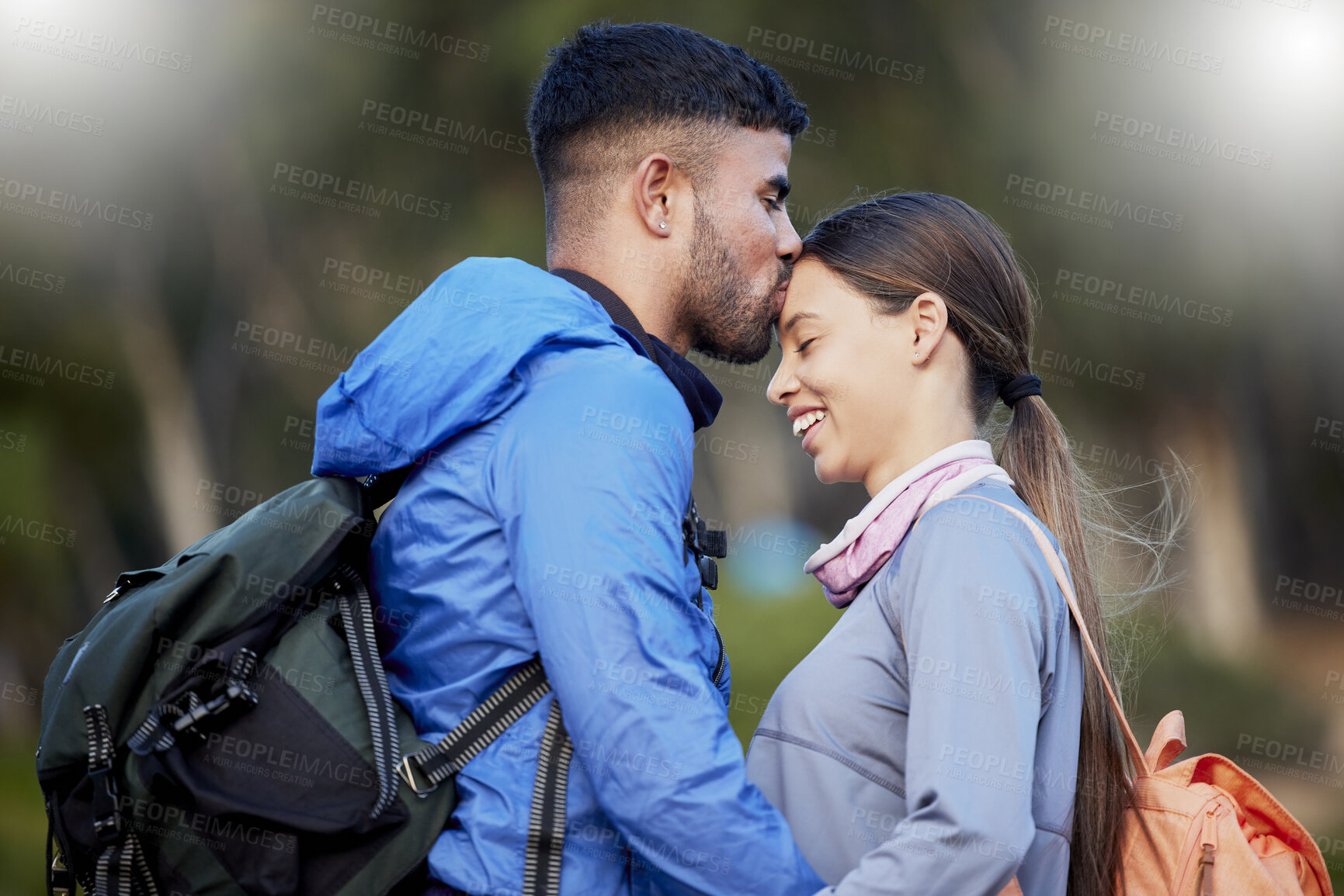 Buy stock photo Man, woman and forehead kiss for hiking, love and happiness in nature for outdoor adventure on holiday. Young happy couple, kissing and smile with care, bonding and vacation in countryside together