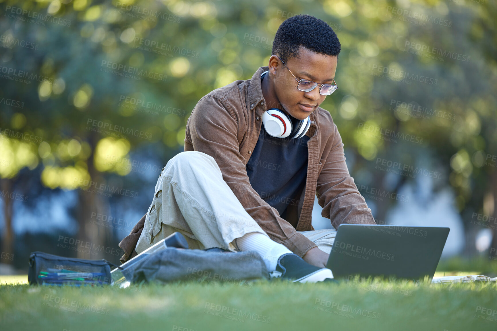 Buy stock photo Black man, park studying and laptop work in a campus garden working on web education. Outdoor, happiness and online elearning with a textbook of a student busy with exam study on university grass