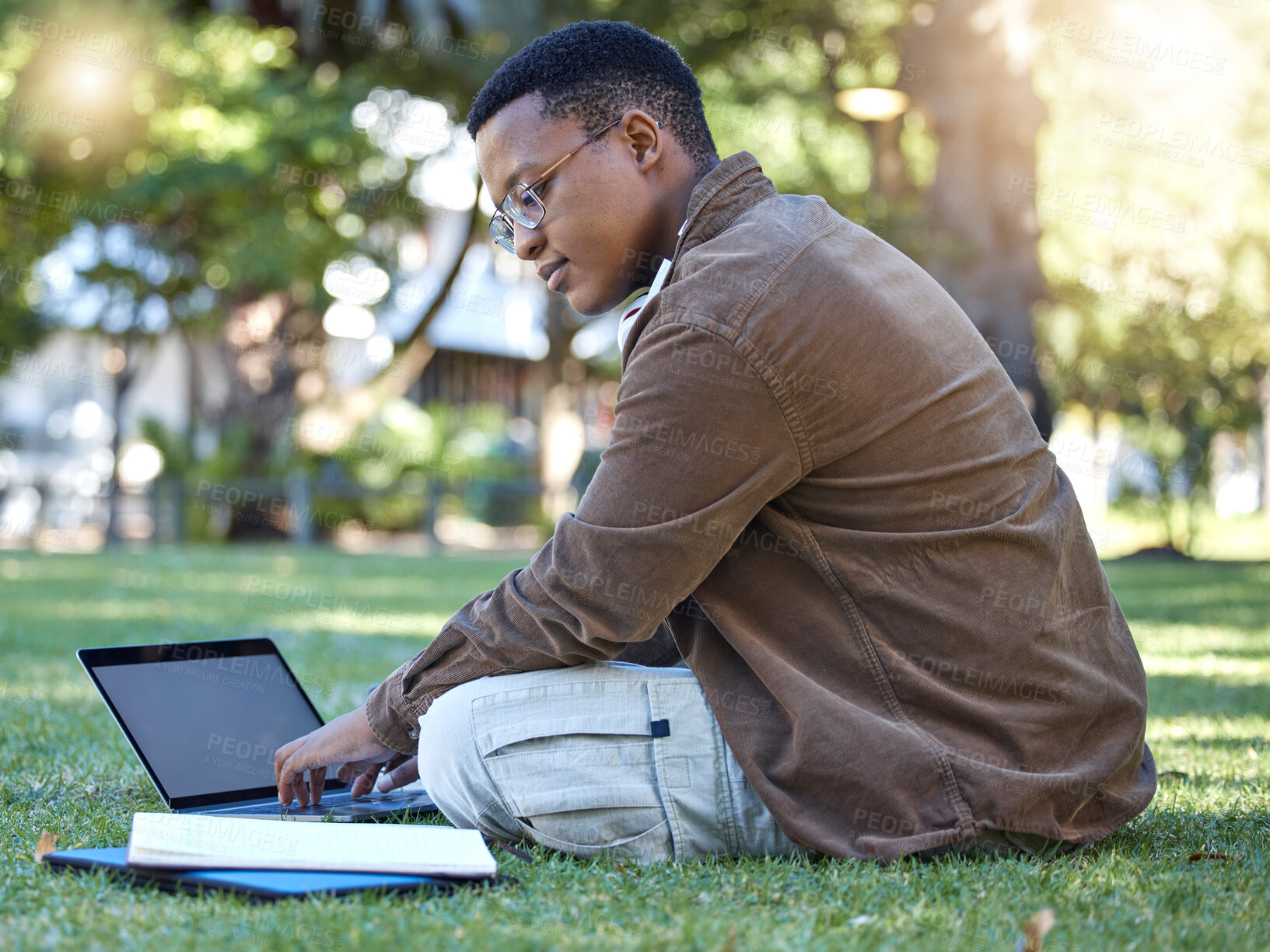 Buy stock photo Black man reading, park and student laptop work in a garden with a education book and lens flare, Outdoor, happiness and elearning with a textbook of a person busy with exam study on university grass