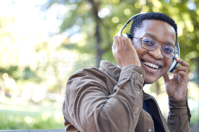 Buy stock photo Headphones, park and portrait of african man listening to music for outdoor, mental health and relaxing break in nature. Young, happy student or black person with audio technology in garden or campus