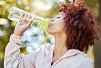 Black woman runner, drinking water and park for summer exercise with curly afro, wellness and hydration. Gen z girl, workout break and bottle in nature for wellness, training and outdoor in sunshine