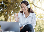 Laptop, wave and business woman in video call with headphones outdoors in park. Computer, hello and happy female entrepreneur, remote worker or freelancer waving in virtual chat, webinar or meeting.