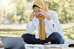 Stress, Islamic and woman student with a headache while studying in a park feeling frustrated and sad outdoors. Laptop, sick and muslim female with an hijab annoyed while learning or reading