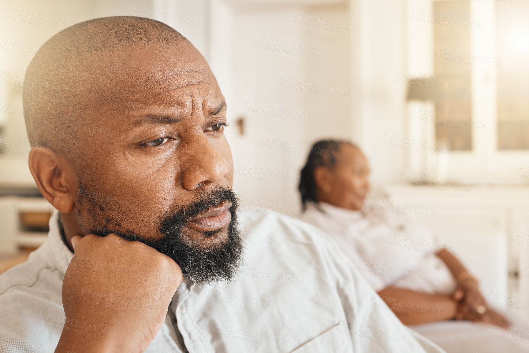 Buy stock photo Face, frustrated or argument and a black man looking angry or upset while thinking about a fight with his wife in their home. Divorce, idea and fighting with a senior couple sitting in a living room