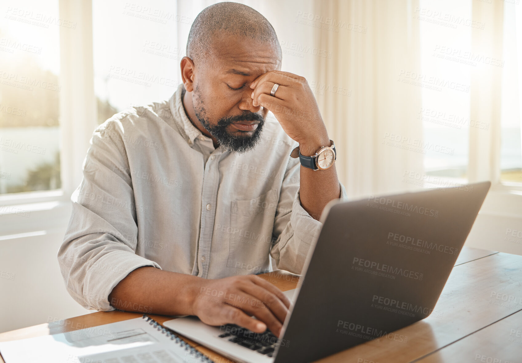 Buy stock photo Black man, laptop and headache in remote work suffering from burnout, stress or anxiety at home. Tired African American businessman freelancer with sore head, pain or strain by computer on table