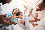 Tickle, laugh and relax with black family in bedroom for bonding, playful and affectionate. Funny, happiness and crazy with parents playing with children at home for wake up, morning and silly
