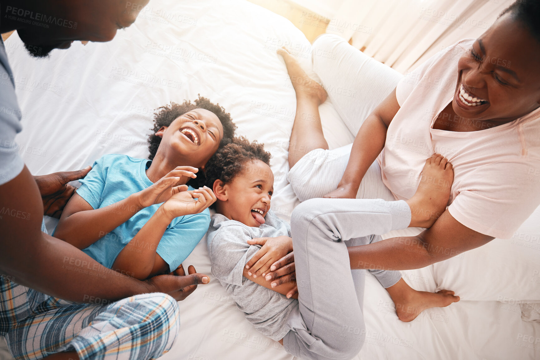 Buy stock photo Tickle, laugh and relax with black family in bedroom for bonding, playful and affectionate. Funny, happiness and crazy with parents playing with children at home for wake up, morning and silly