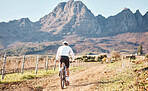 Back of man, mountains and cycling in nature, countryside and training for triathlon, sports and race in Cape Town. Cyclist, mountain bike and outdoor bicycle for marathon fitness, exercise or cardio