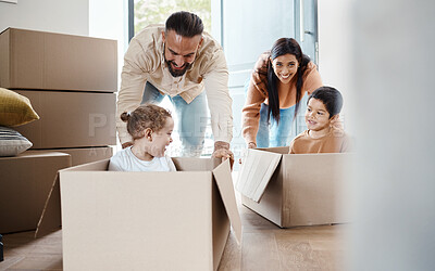 Buy stock photo Playful, fun and a family moving into a house, bonding and unpacking their new home together. Happy, game and young parents pushing their children in a box, playing and relocation to an apartment