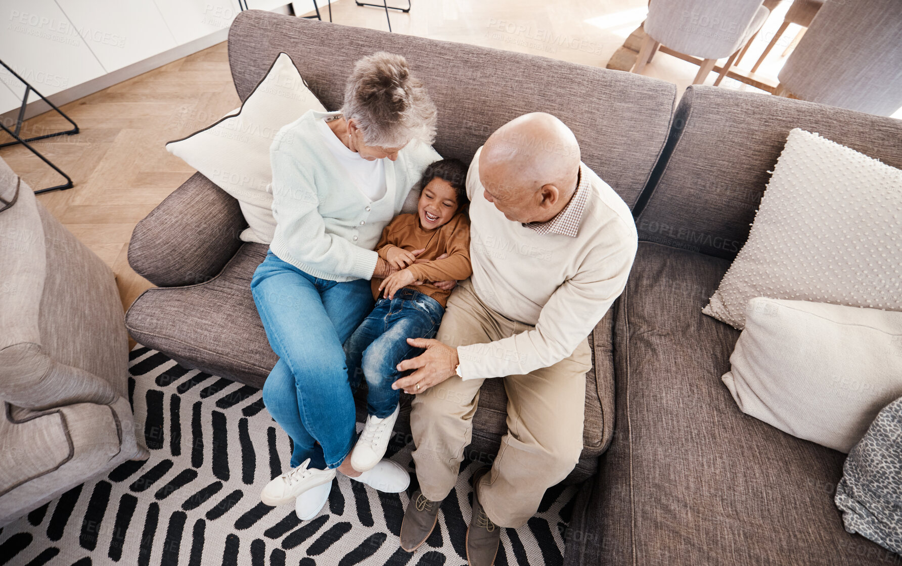 Buy stock photo Relax, playful and child with grandparents on sofa of living room for bonding, affectionate and embrace. Support, care and break with senior people and boy at home for happiness, generations and hug
