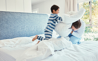 Buy stock photo Playing, dad and son in pillow fight on bed, fun quality time and man bonding with child at home. Smile, happy and play, father and kid in bedroom with pillows, joy and happiness together on weekend.
