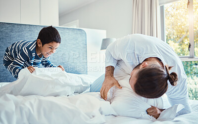 Buy stock photo Happiness, fun and father in pillow fight with his child on the bed in the bedroom of family house. Love, smile and happy dad being playful with his boy kid while bonding and playing  at their home.