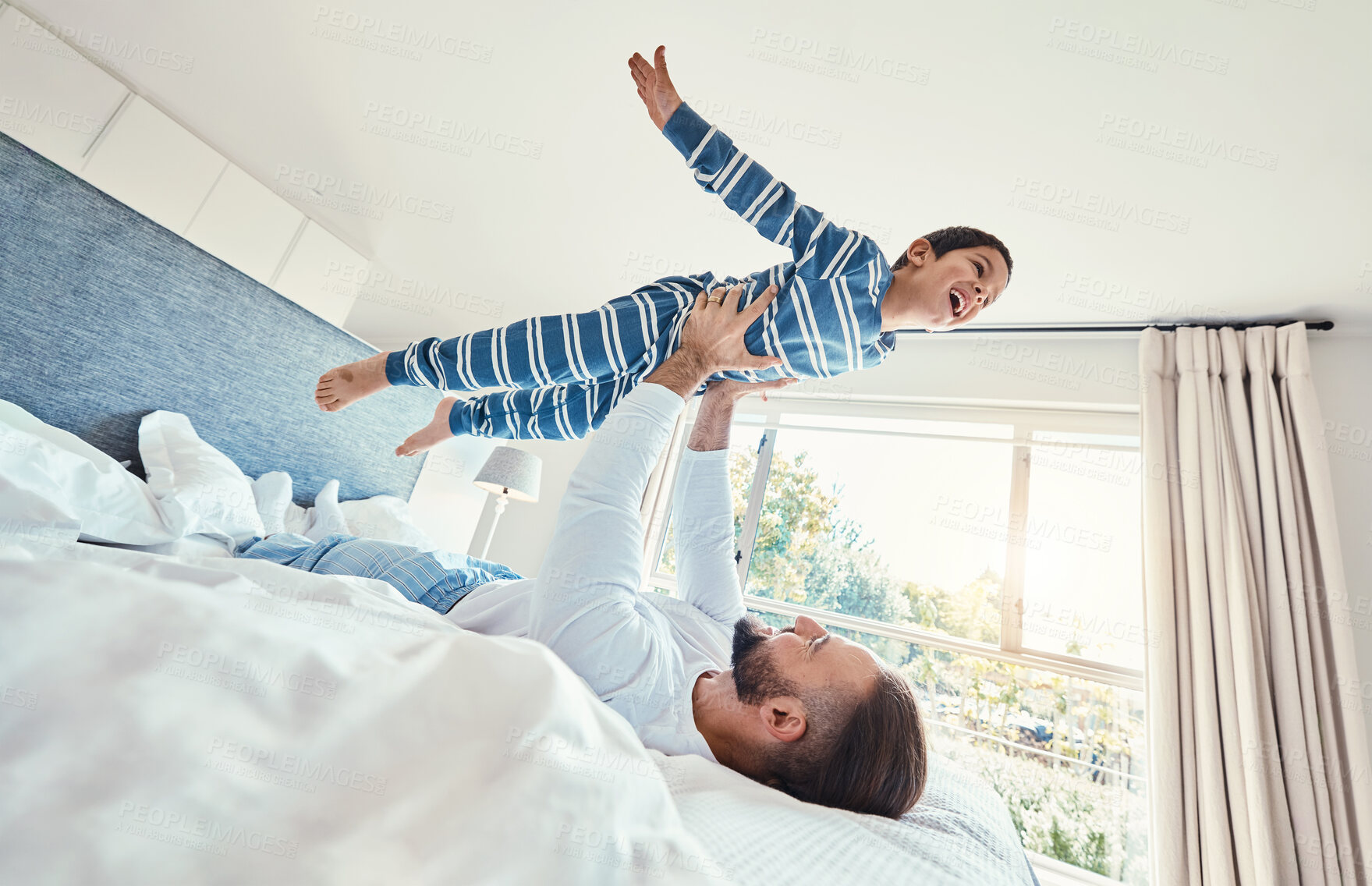 Buy stock photo Father, son and dad playing with his child on a bed holding him having fun in a bedroom feeling happy, carefree and excited. Parent, kid and dad bonding with young boy in a house together 