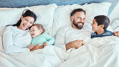 Buy stock photo Waking up, bed and family relax, happy and bond while resting, talking and laughing from above at home. Bedroom, fun and kids with parents in the morning, playful and caring while lying and embracing