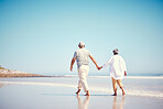 Holding hands, beach and an old couple walking outdoor in summer with blue sky mockup from behind. Love, romance or mock up with a senior man and woman taking a walk on the sand by the ocean or sea