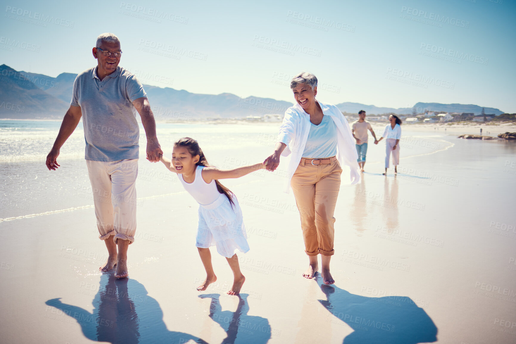 Buy stock photo Beach, holding hands and playing, grandparents with girl, family walking on ocean sand together. Fun, vacation and happy senior man and woman with children bonding, quality time and summer in nature.
