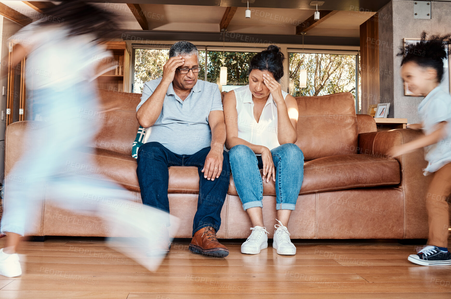 Buy stock photo Kids running, stress and grandparents on sofa tired and chaos in living room with frustrated grandpa and grandma. Parenting burnout, hyperactive children playing in home with old woman and man