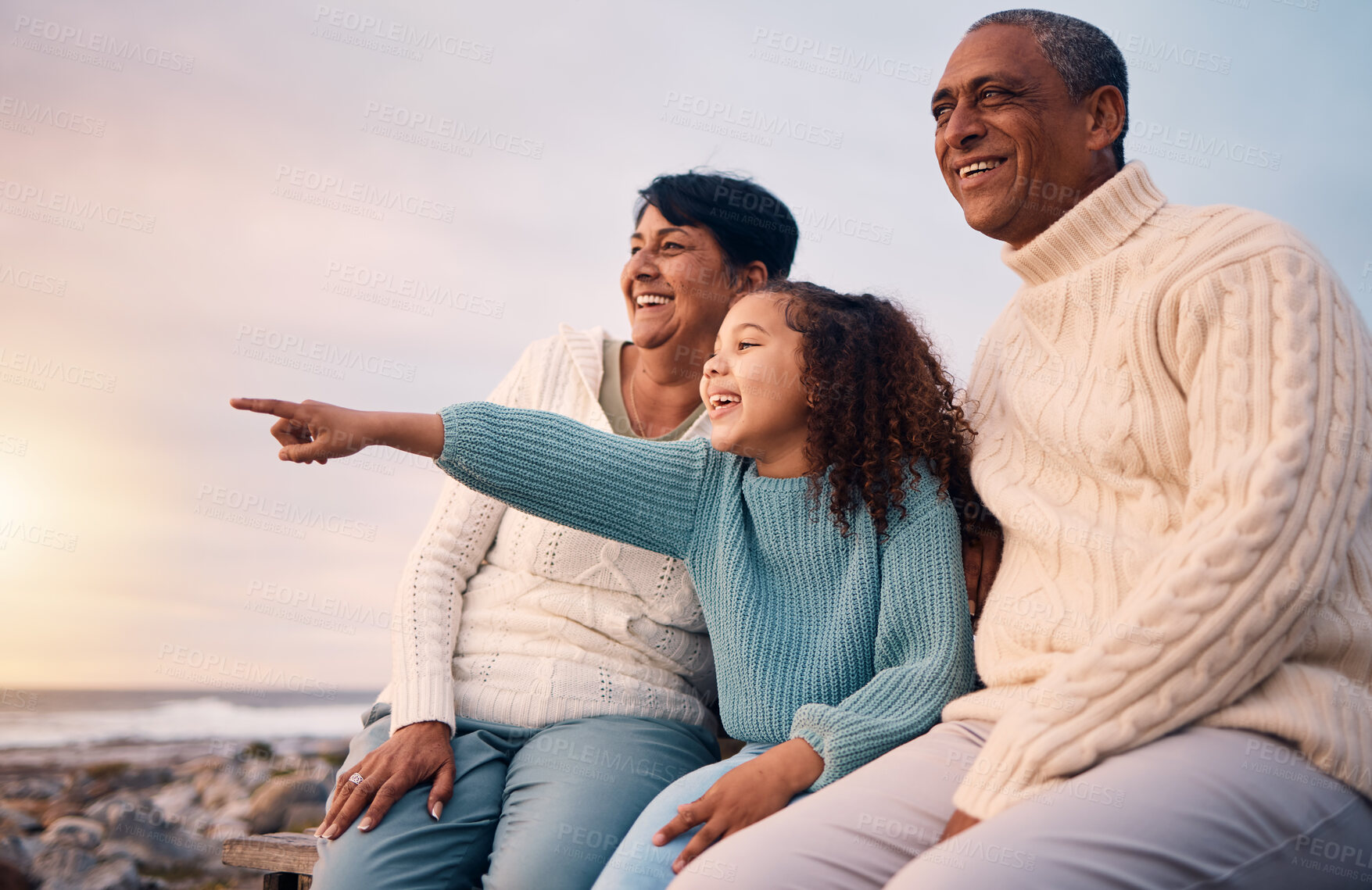 Buy stock photo Beach, black family and a girl pointing outdoor with grandparents while looking at the view together during sunset. Nature, summer or kids with a senior man and woman bonding with their grandchild
