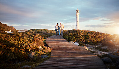 Buy stock photo Lighthouse, family walking and nature adventure on a summer holiday at sunset by the sea. Ocean, beach walk and outdoor with a mom, father and child together with love and parents support at dusk