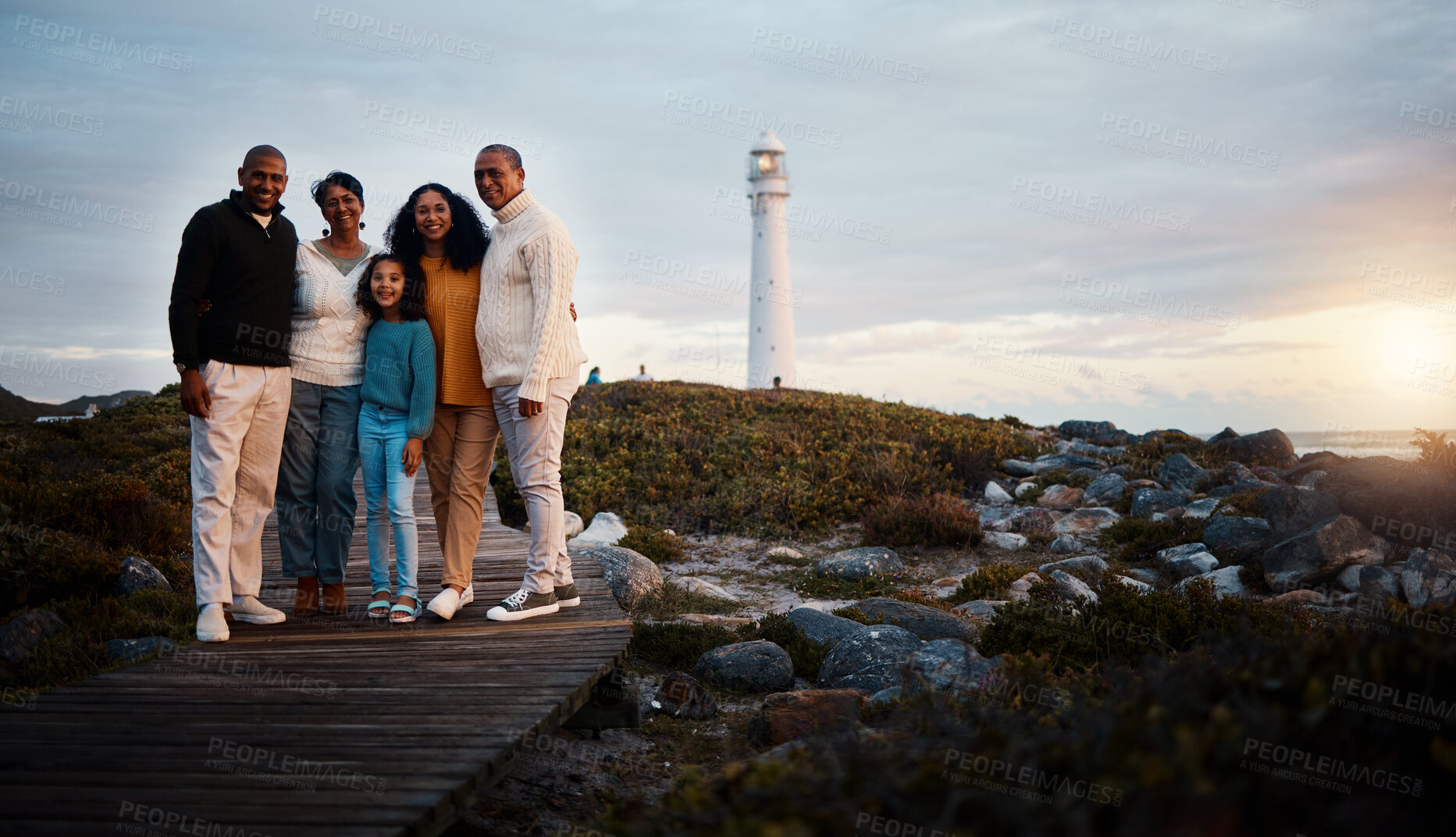 Buy stock photo Big family, portrait walking and nature bonding on a holiday at sunset by a sea lighthouse. Ocean, beach walk and outdoor with a mom, father and child together with love and parents support at dusk