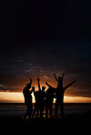 Carefree, sunset and silhouette of friends at the beach while on a summer vacation, adventure or weekend trip. Freedom, happy and shadow of group of people having fun together by the ocean on holiday