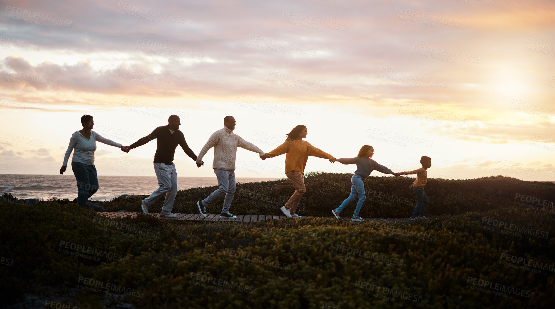 Buy stock photo Family holding hands and walking in nature for group support, growth development and adventure together in sunset. Children with grandparents for fitness, health and running by a park path or ocean 